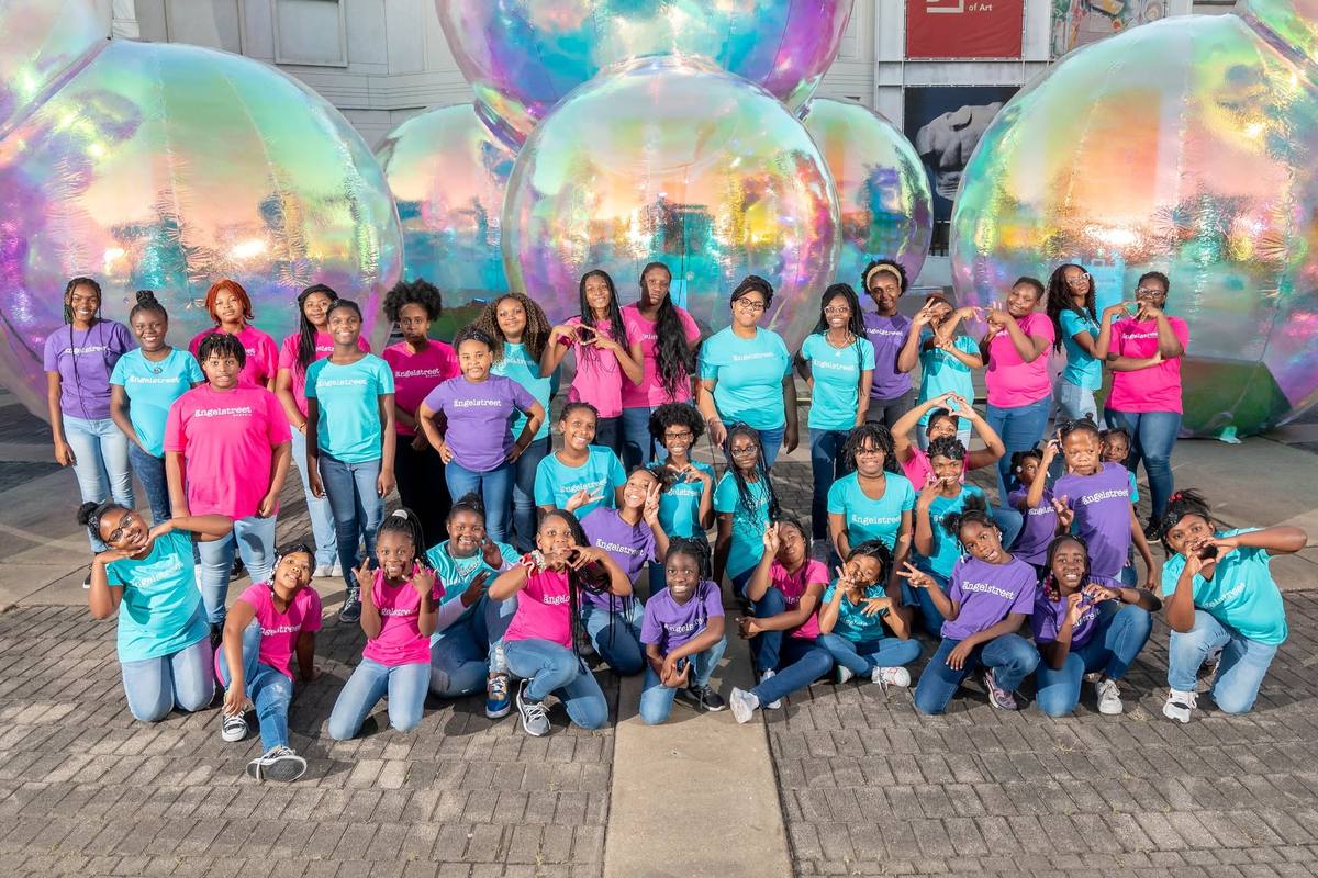 AngelStreet girls posing together in pink, teal and purple program shirts